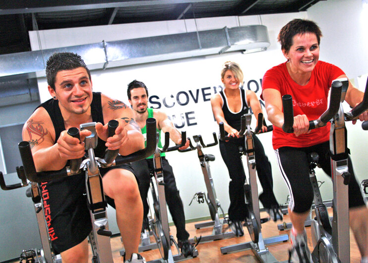 Group indoor cycling class with riders on spin bikes